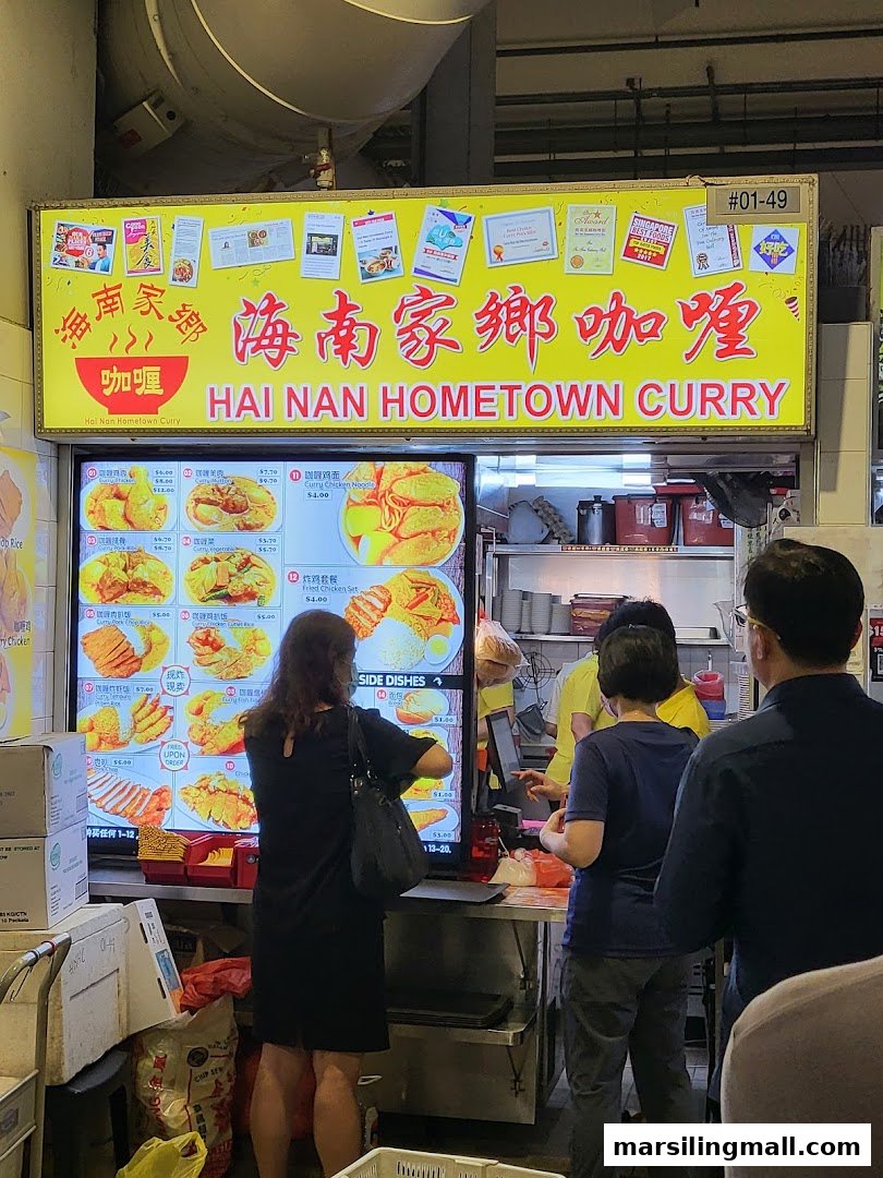 Customers order at Hai Nan Hometown Curry, featuring a bright sign and digital menu board.