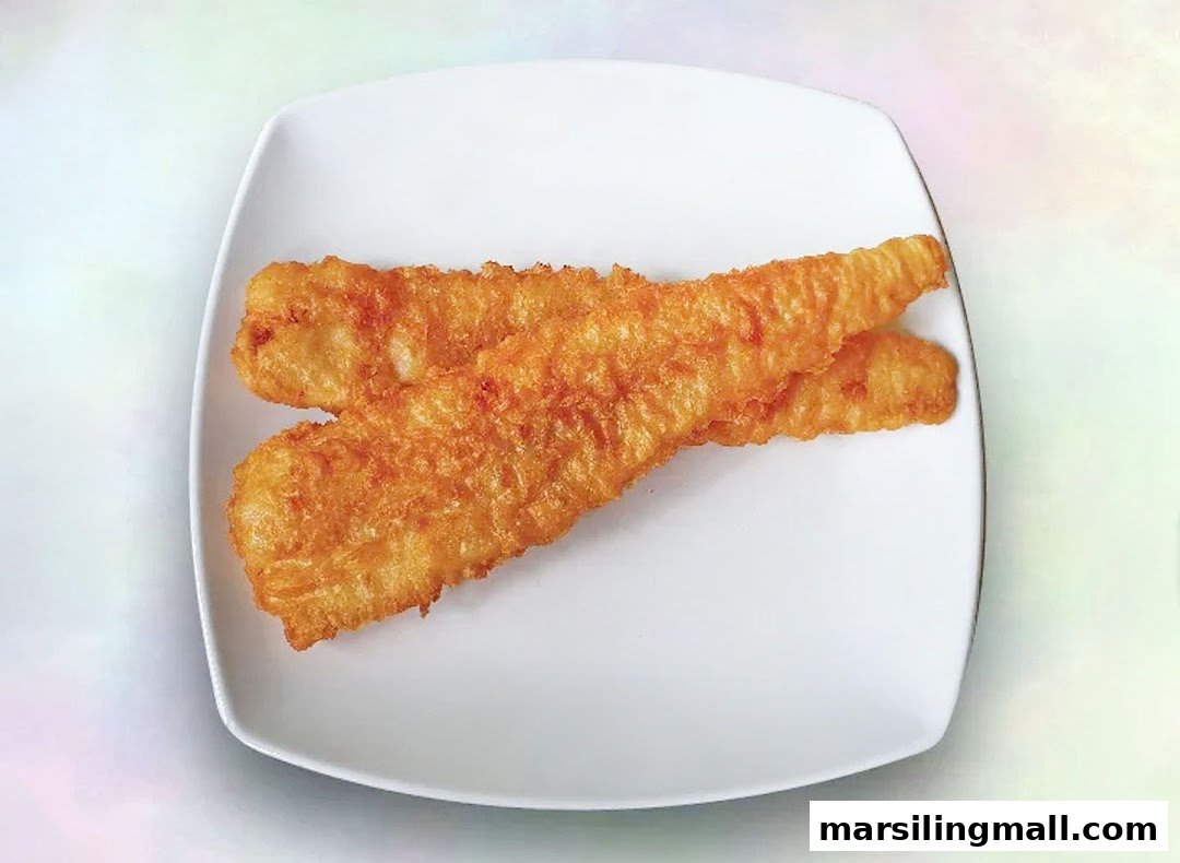 Two golden-brown fried fish fillets are presented on a clean white rectangular plate.