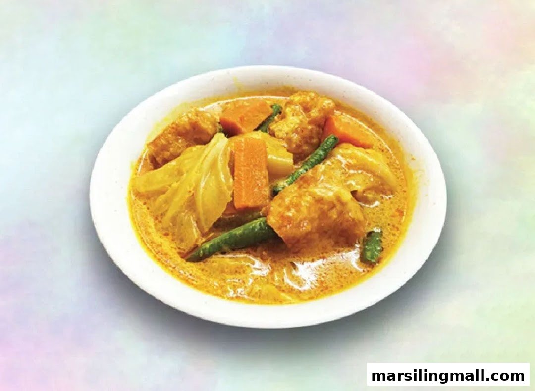 A vibrant bowl of Hainanese curry with vegetables and tofu puffs in a rich, golden sauce.