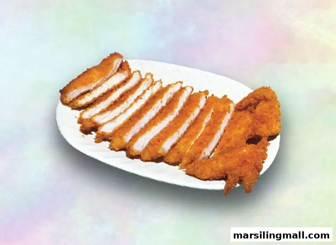 A white plate holds several slices of golden-brown fried chicken cutlet and crispy fried chicken pieces.