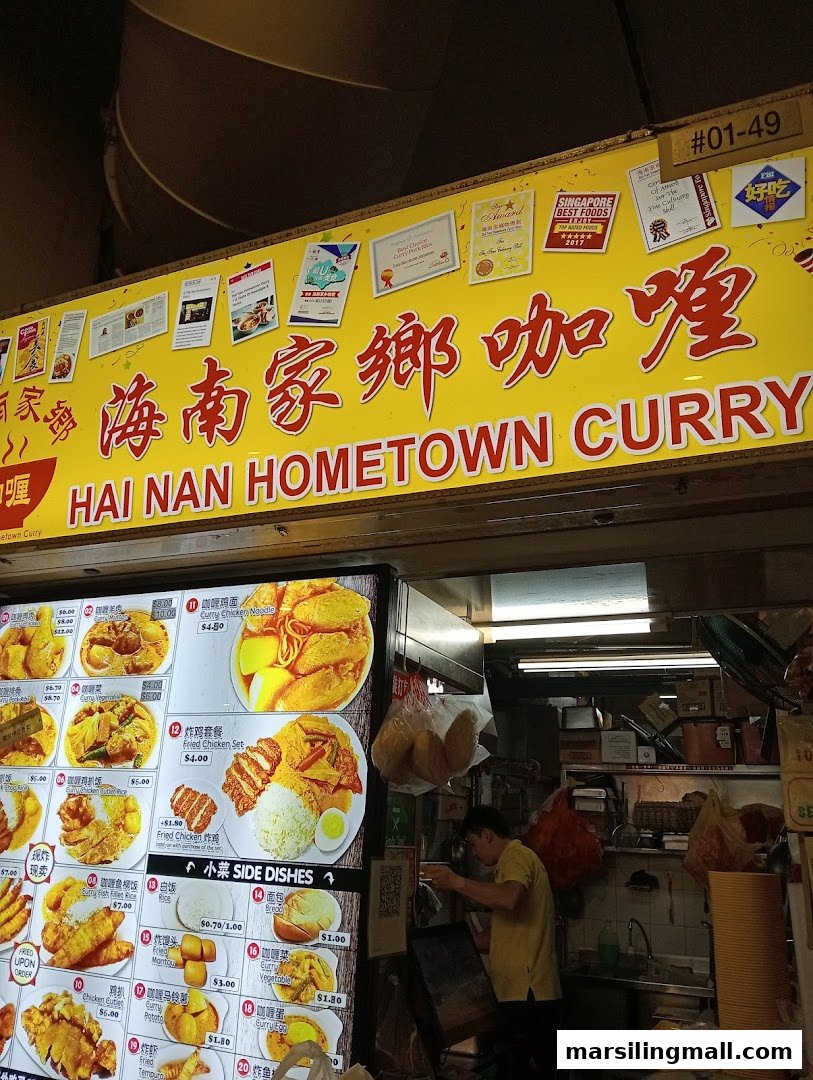 A vibrant image of Hai Nan Hometown Curry stall, showcasing its menu display and a staff member.