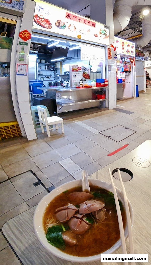 A food stall named 'Herbal Soup Pig Trotter' with a bowl of noodles in the foreground.