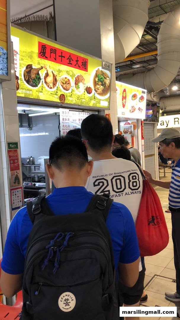 Customers queueing at a food stall featuring a large menu board with traditional Chinese dishes.