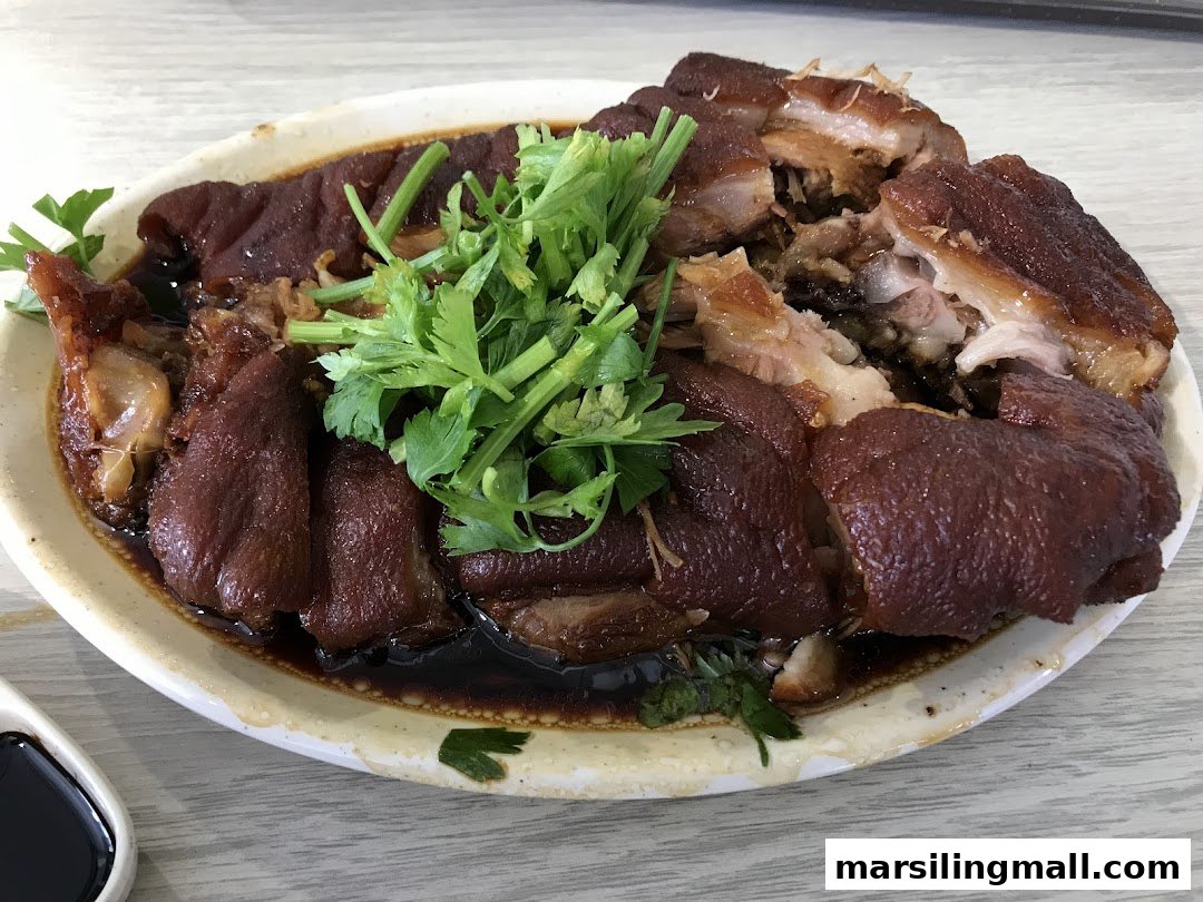 A plate of braised pig trotters garnished with fresh cilantro, served in a rich dark sauce.