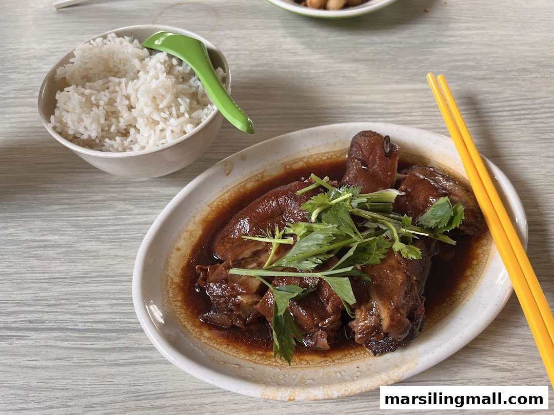 A plate of braised pig trotters with cilantro and a bowl of white rice.