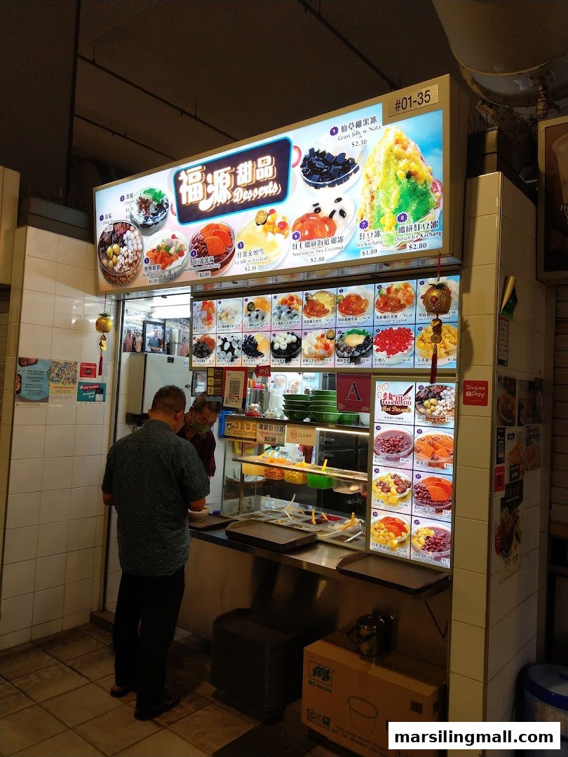 A vibrant dessert stall named Hock Guan Desserts with a prominent menu board and customers.