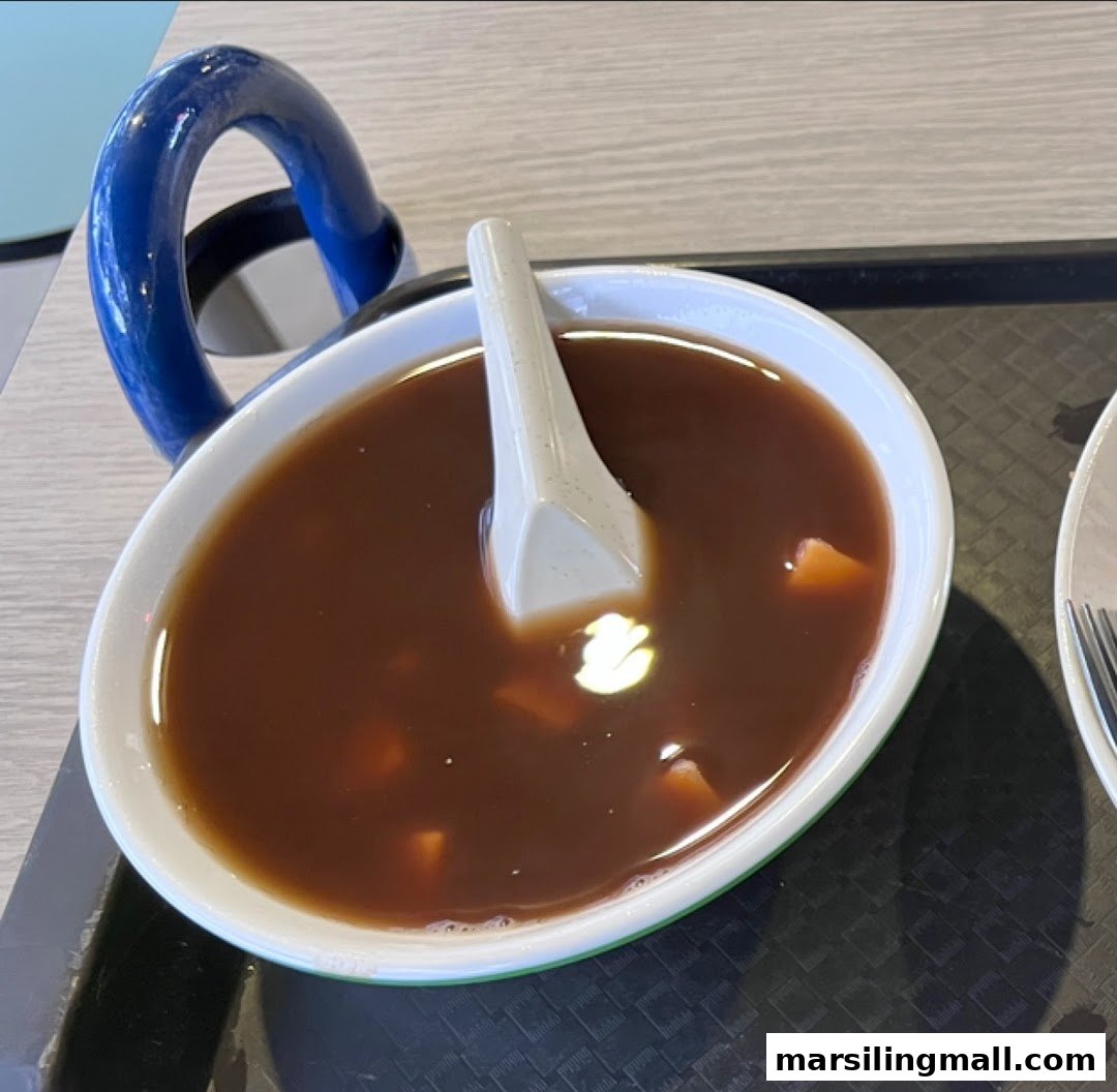 A close-up of a bowl of traditional red bean dessert soup with a spoon on a tray.