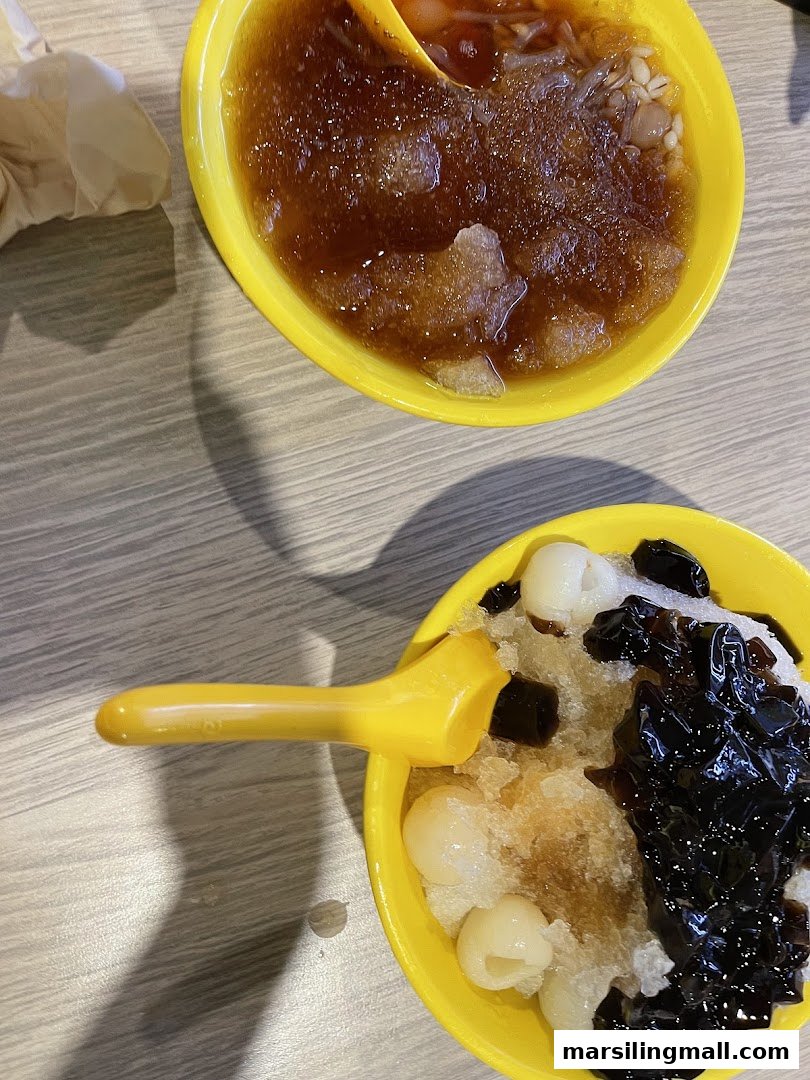 Two vibrant yellow bowls filled with refreshing Asian shaved ice desserts and various toppings.