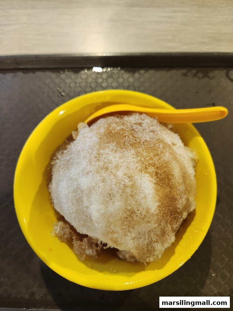A yellow bowl filled with brown sugar shaved ice dessert and a yellow spoon.