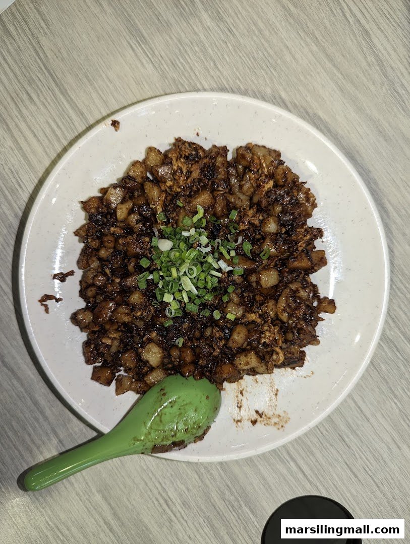 A plate of dark fried carrot cake topped with spring onions, ready to be enjoyed.