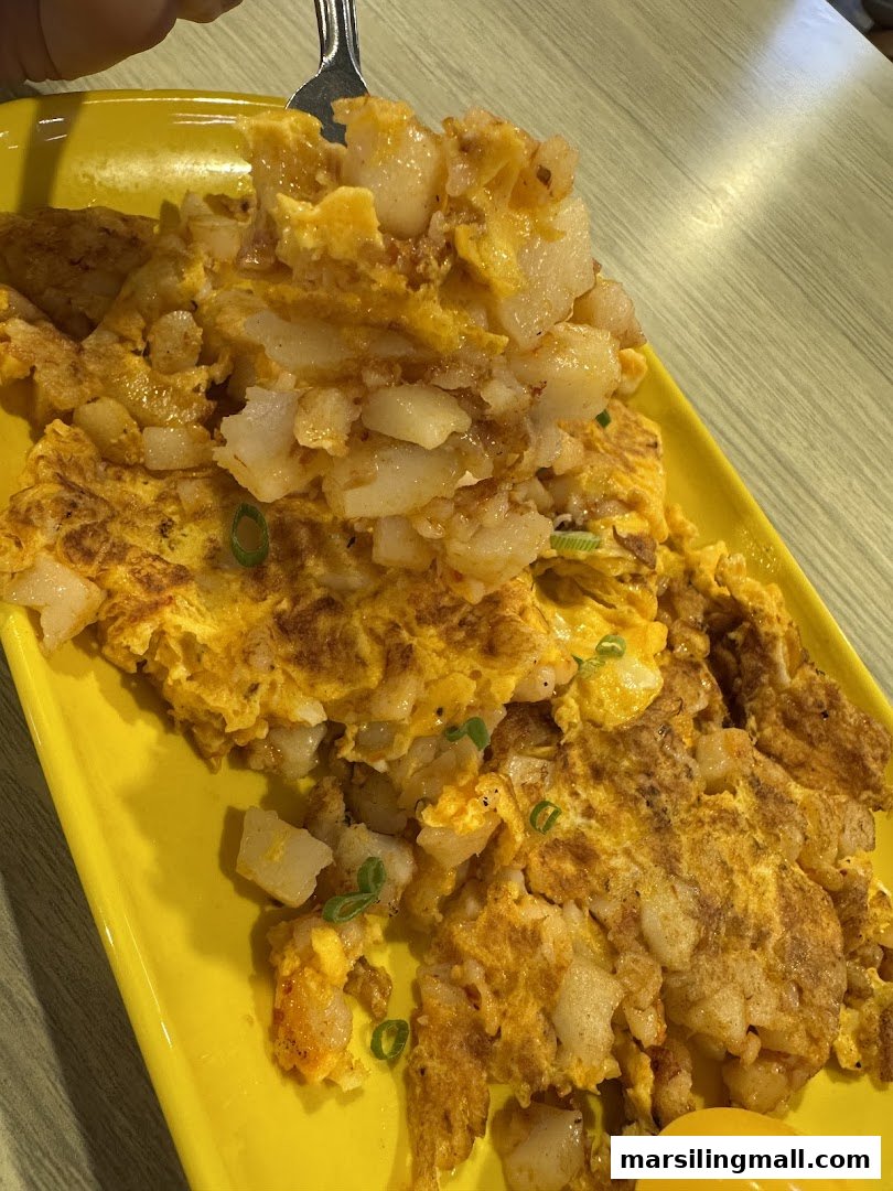 A close-up of a serving of fried carrot cake with egg and spring onions on a bright yellow plate.