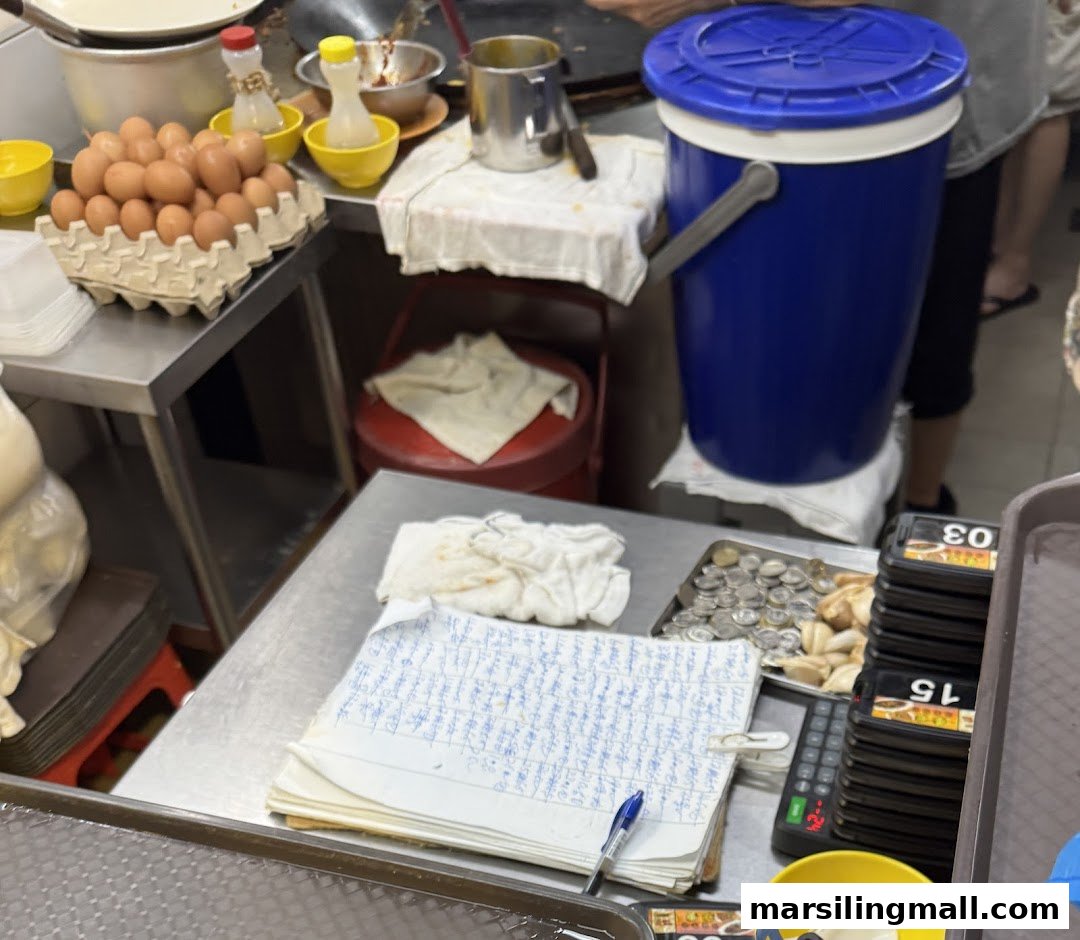 A bustling food stall kitchen counter with fresh eggs, cooking ingredients, and order slips.