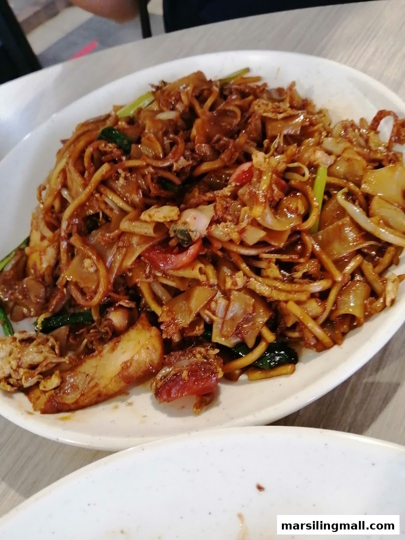 A close-up of a delicious plate of fried noodles with various ingredients, likely char kway teow.