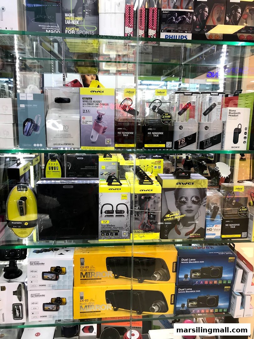 A display case showcasing a wide range of mobile and car electronic accessories, including headphones, chargers, and DVRs.