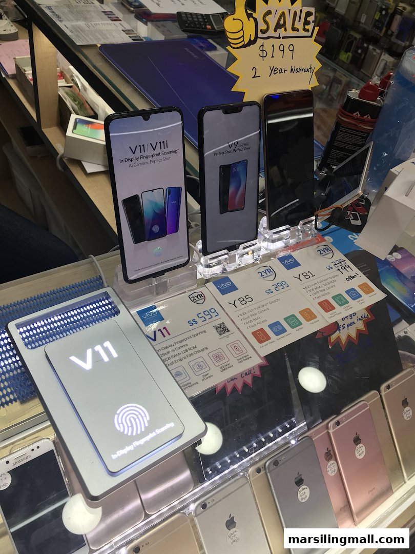 A display of various smartphones, including Vivo and iPhones, showcasing features and sale prices in a retail store.