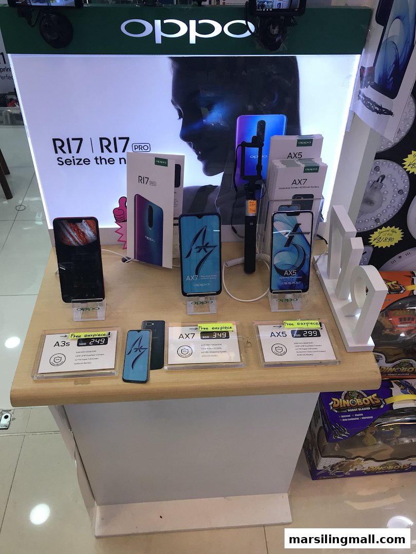 An illuminated retail display showcasing various OPPO smartphones, including R17, AX7, AX5, and A3s models, with pricing.