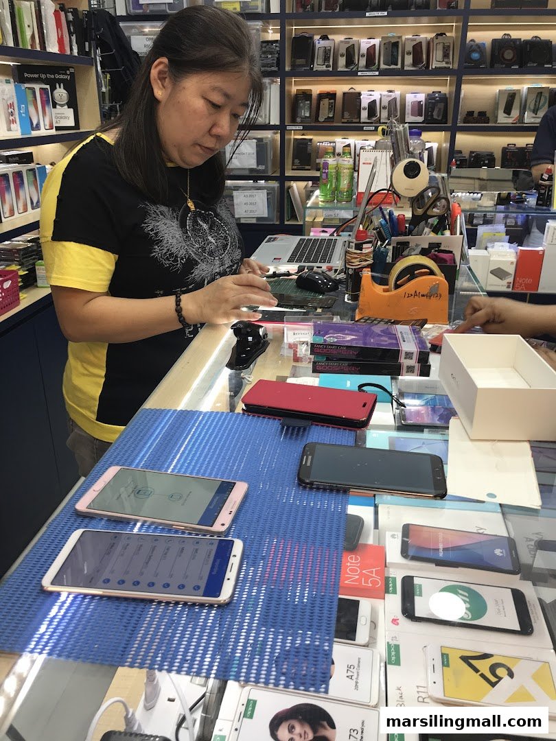 A customer interacts with mobile phones and accessories at the ImobileHub counter, showcasing various devices.