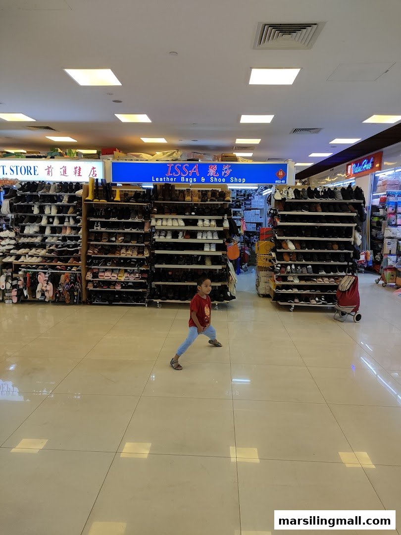 Interior view of Issa Leather Bags & Shoes Shop, showcasing numerous shoes on display shelves with a child in the foreground.