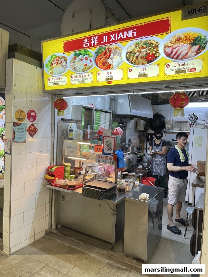 A bustling food stall named Ji Xiang, featuring its menu board and staff at work.
