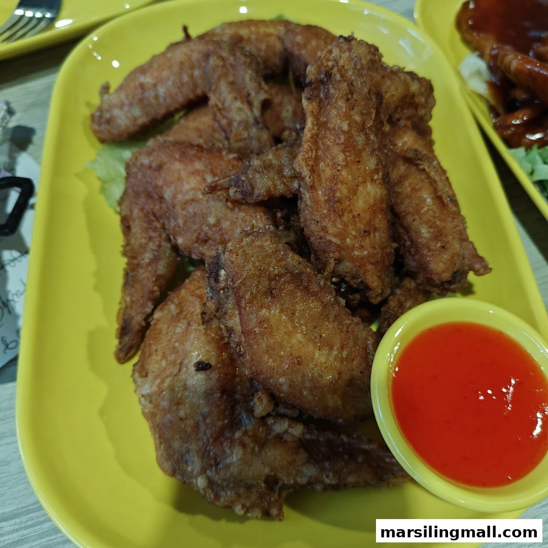 A vibrant yellow plate filled with crispy fried chicken wings and a side of red chili dipping sauce.