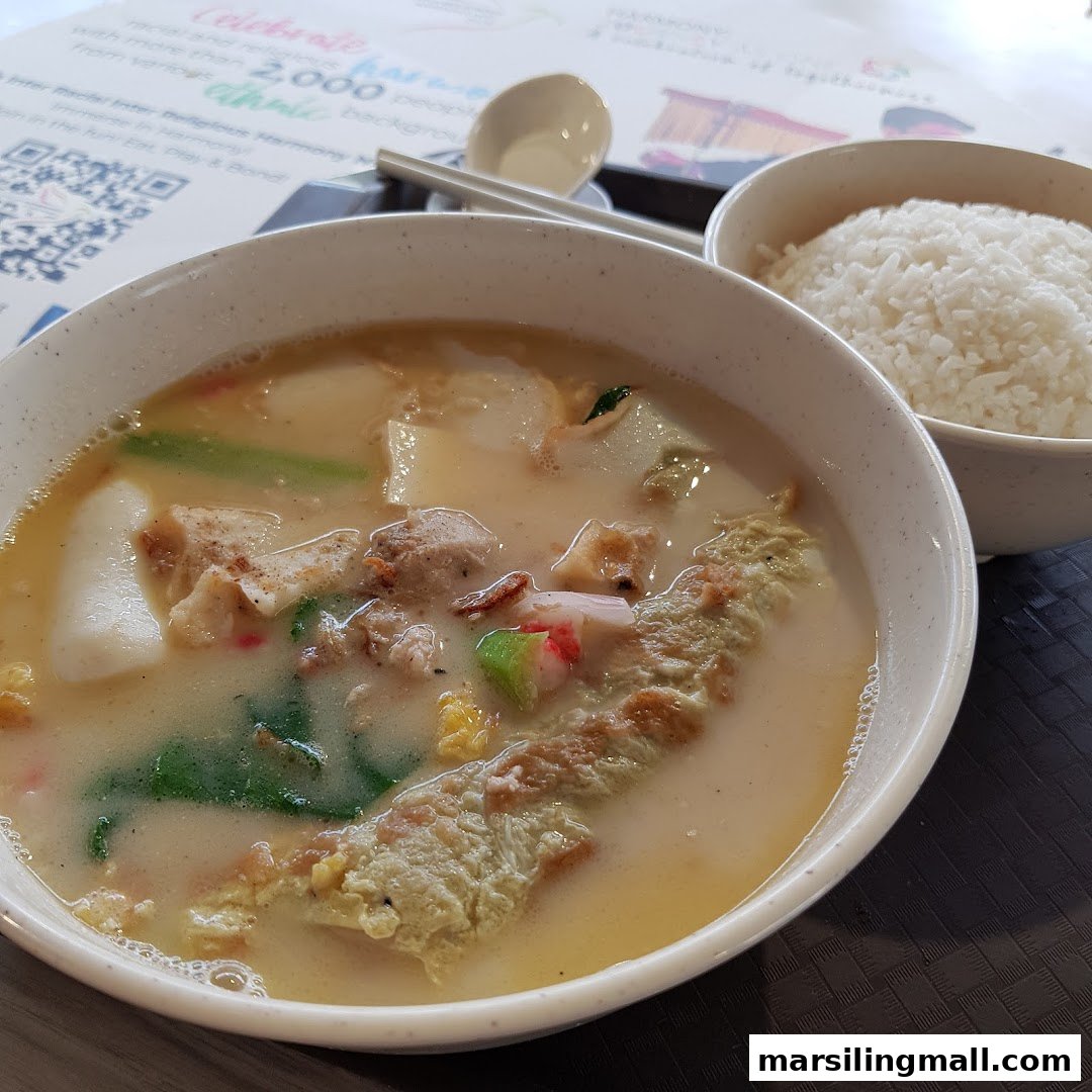 A hearty bowl of soup with various ingredients and a side of white rice.
