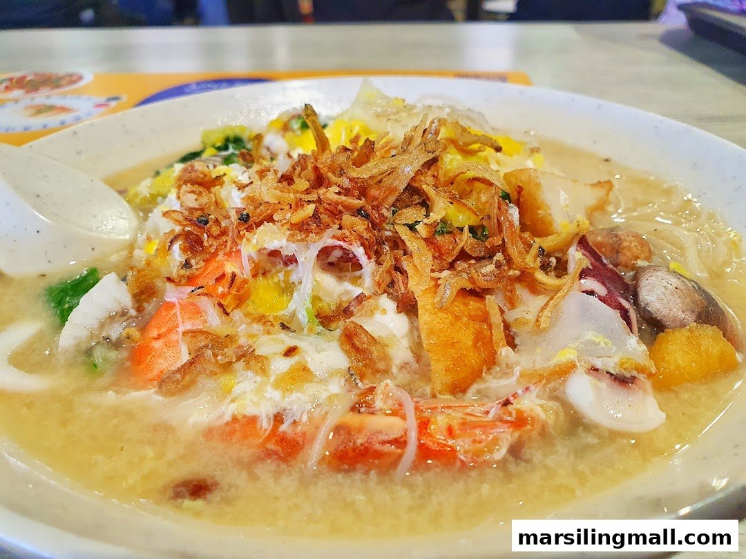 A close-up of a hearty seafood noodle soup topped with crispy fried shallots and fresh ingredients.