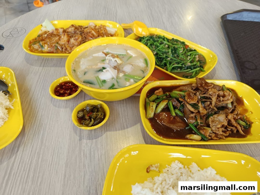 A vibrant spread of cooked food dishes, including soup, stir-fried vegetables, and meat, served on yellow plates.