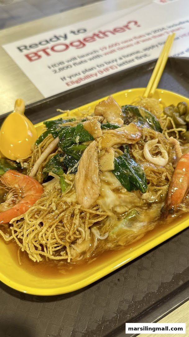 A vibrant plate of crispy noodles with seafood, chicken, and vegetables in a rich gravy.