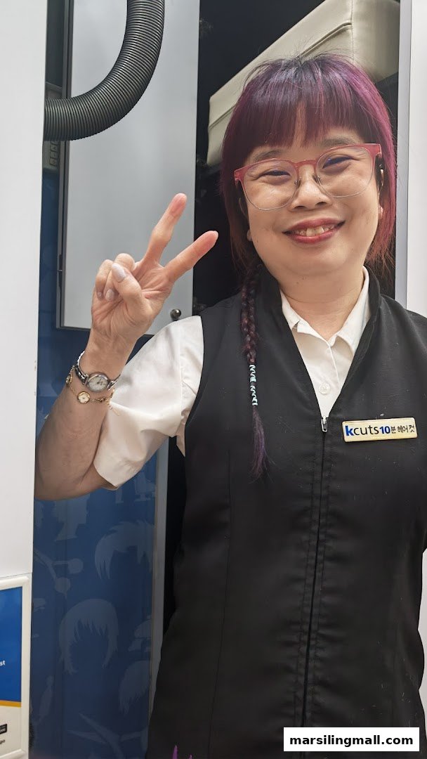A friendly kcuts staff member smiles and makes a peace sign.