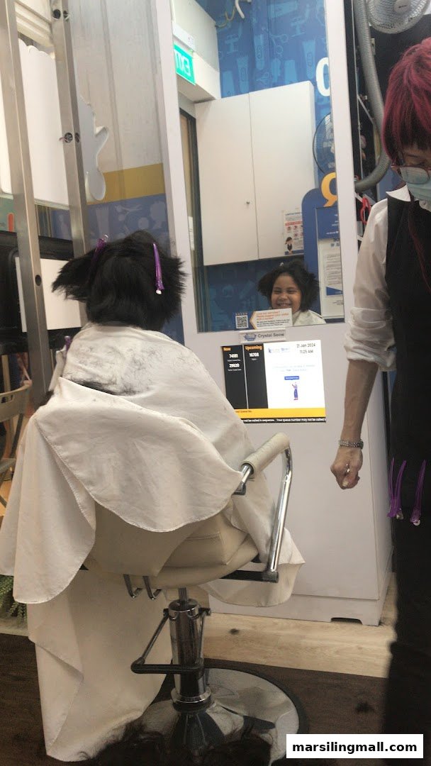 A customer receives a haircut at kcuts, with hair clippings on the floor and a stylist nearby.