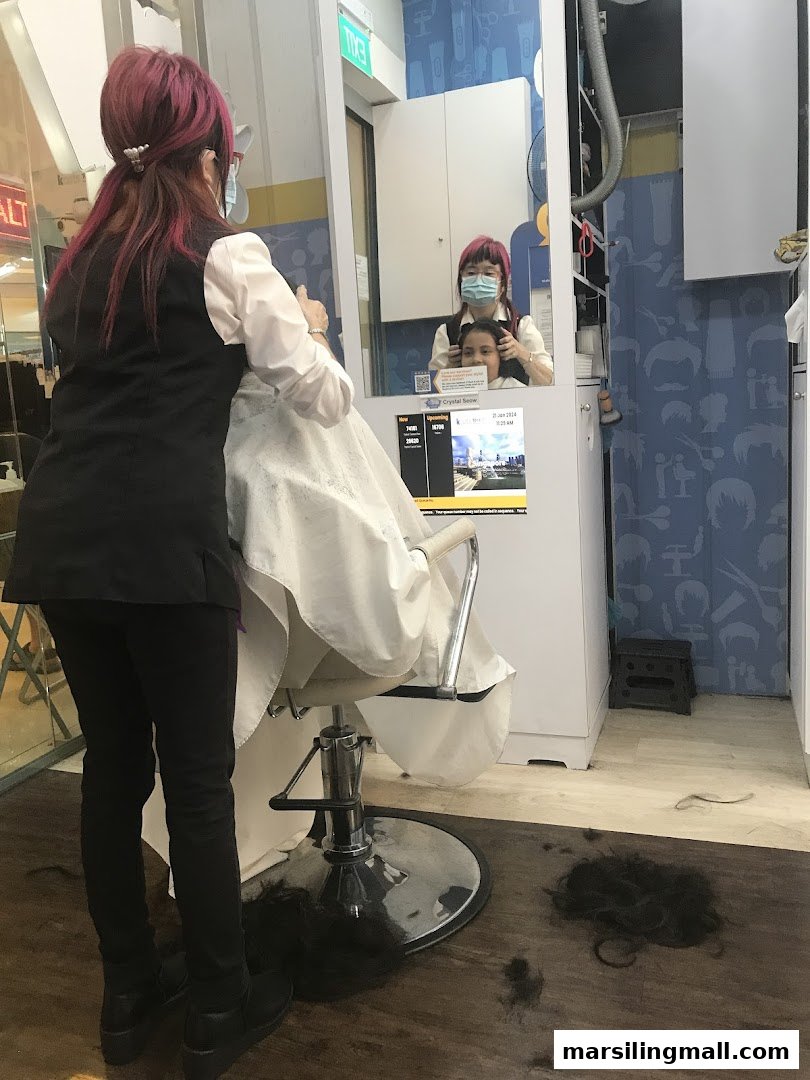 A stylist with pink hair cuts a customer's hair in a modern salon.