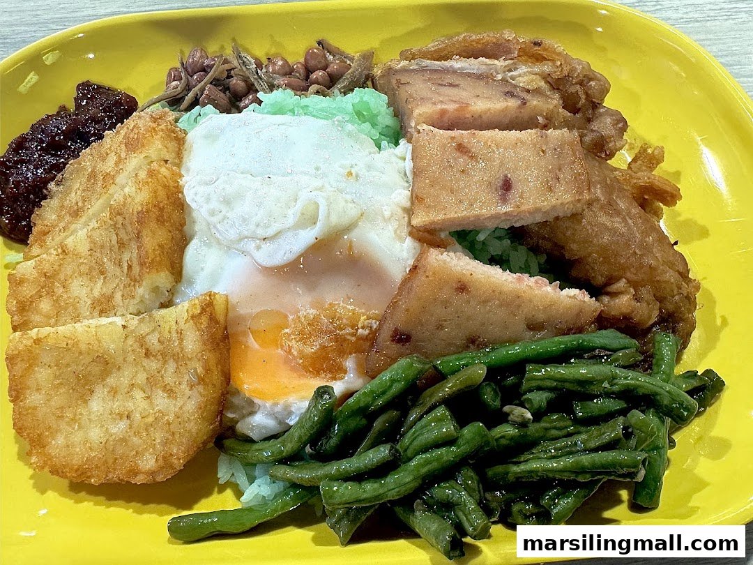 A vibrant plate of Nasi Lemak with fried chicken, egg, hash browns, green beans, sambal, anchovies, and peanuts.