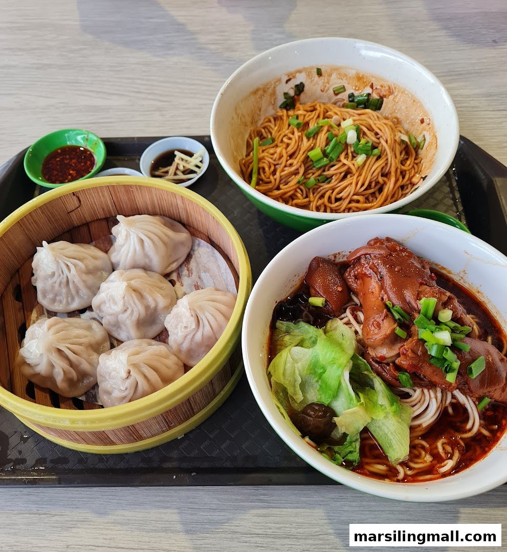 A tray with xiao long bao, dry noodles, and braised pork trotters with noodles.