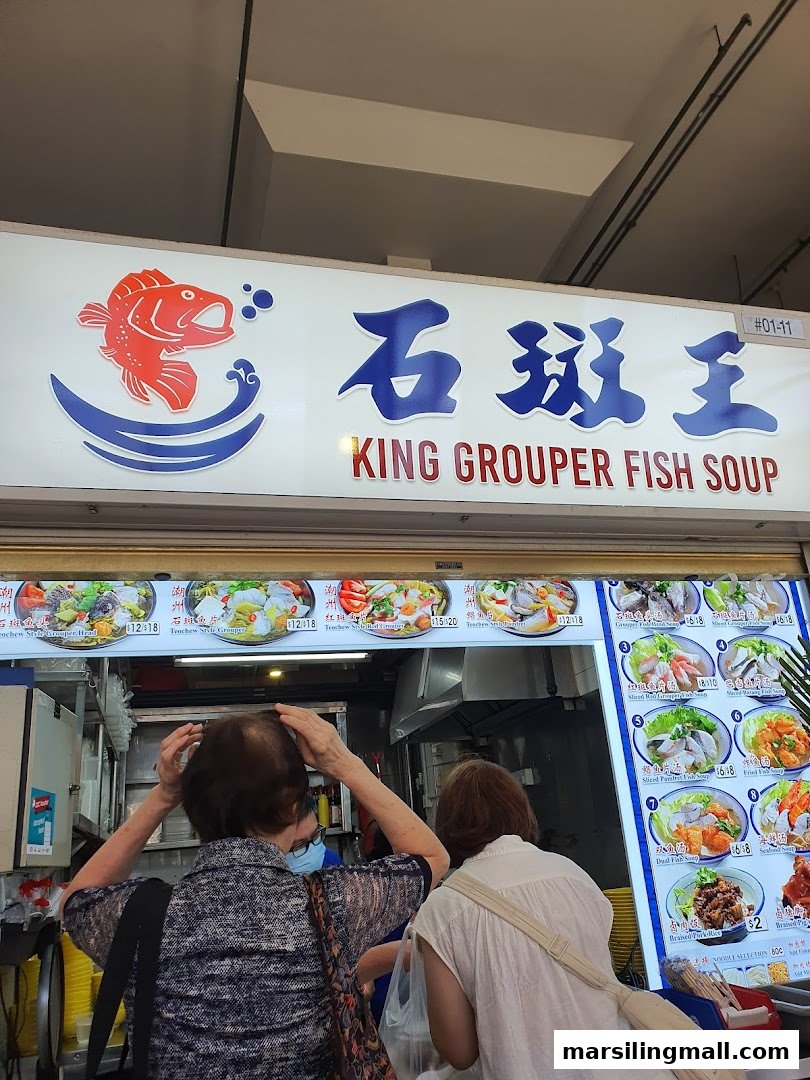 A hawker stall named 'King Grouper Fish Soup' with customers queuing to order.