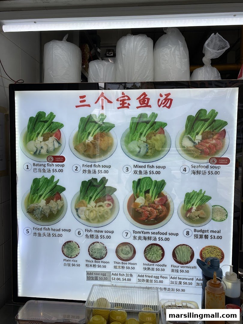 A brightly lit menu board showcasing various fish and seafood soup dishes with prices and add-ons.