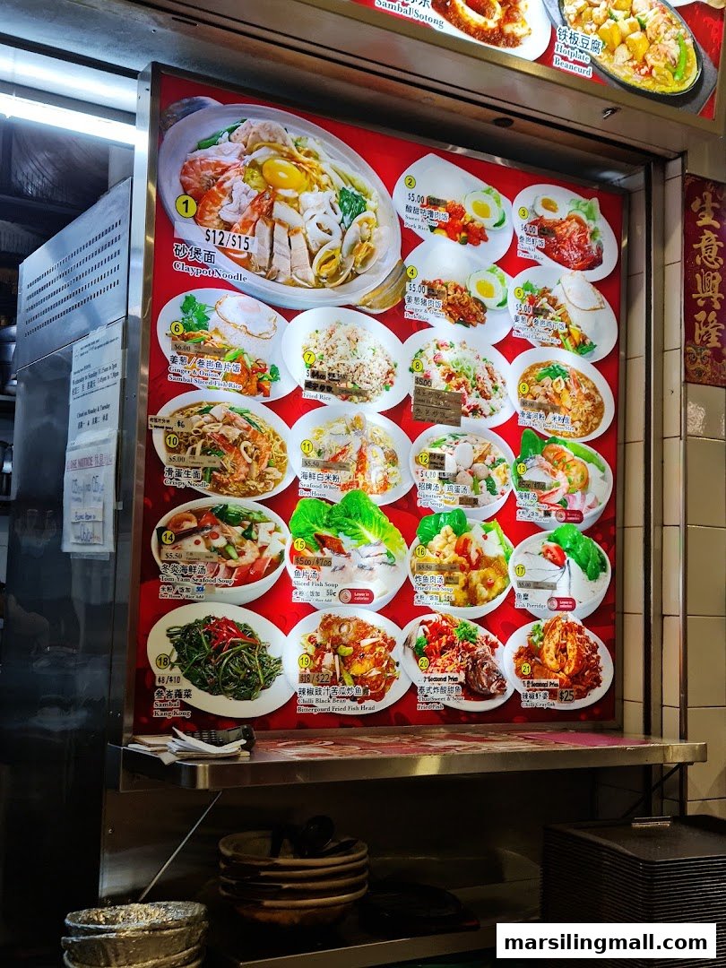A vibrant menu board displaying various Asian dishes with photos and prices at a hawker stall.