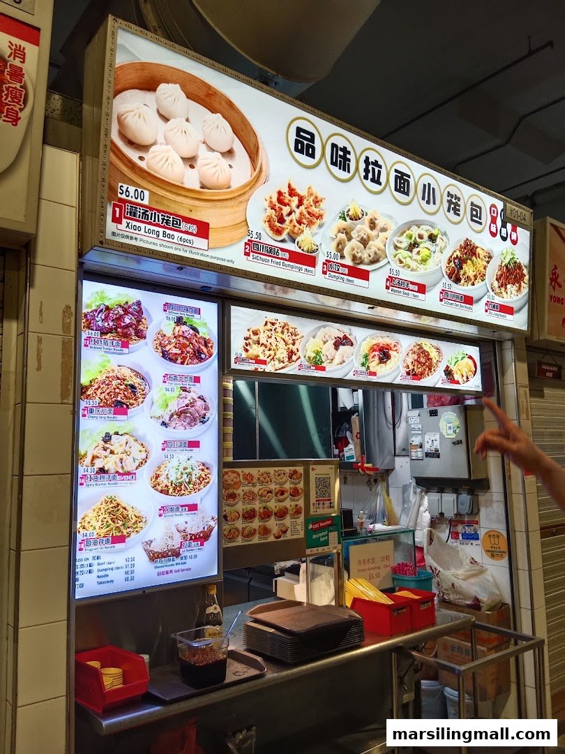A hawker stall's illuminated menu boards displaying various Chinese noodles and dumplings.