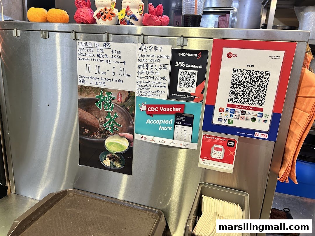 A hawker stall counter displaying menu items, payment options, and promotional signs.