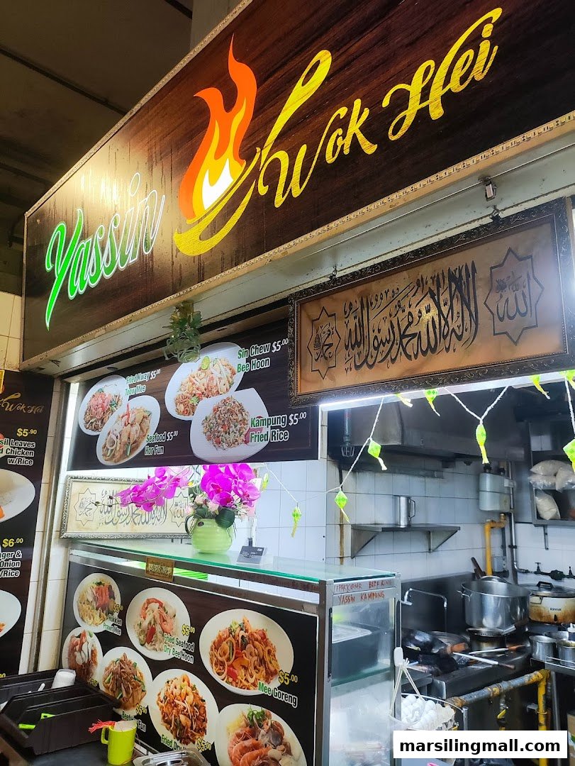 A vibrant hawker stall, Yassin Wok Hei, showcasing its menu and bustling kitchen area.