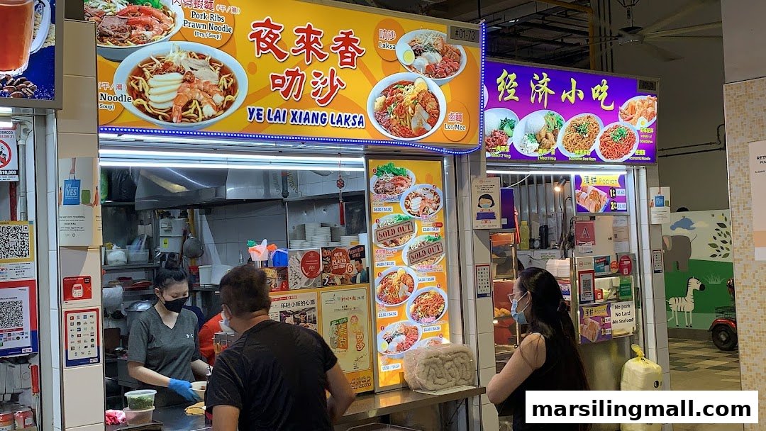 A bustling hawker stall, 'Ye Lai Xiang Laksa', serving local noodles and economic rice dishes.