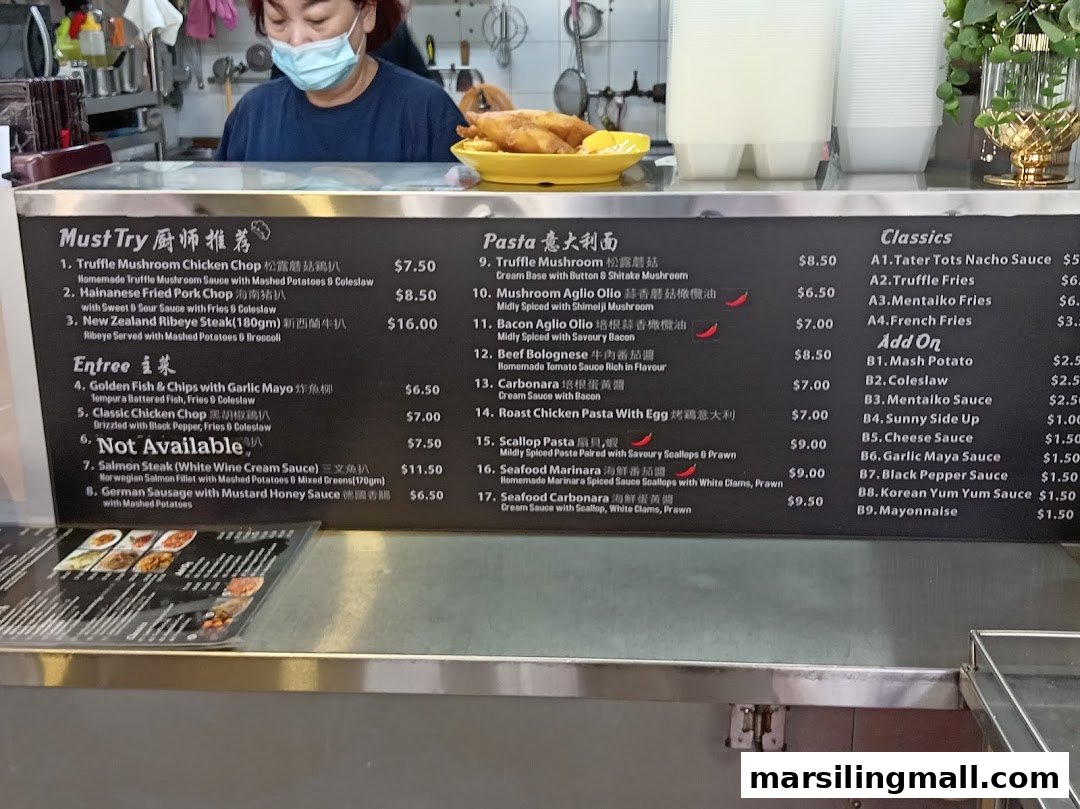 A hawker stall menu board displaying a variety of Western dishes, with a staff member in the background.