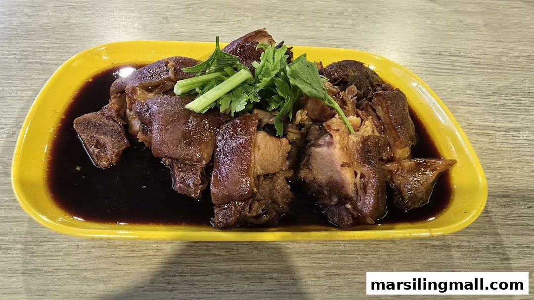 A plate of braised pork trotters with dark sauce and garnished with fresh coriander.