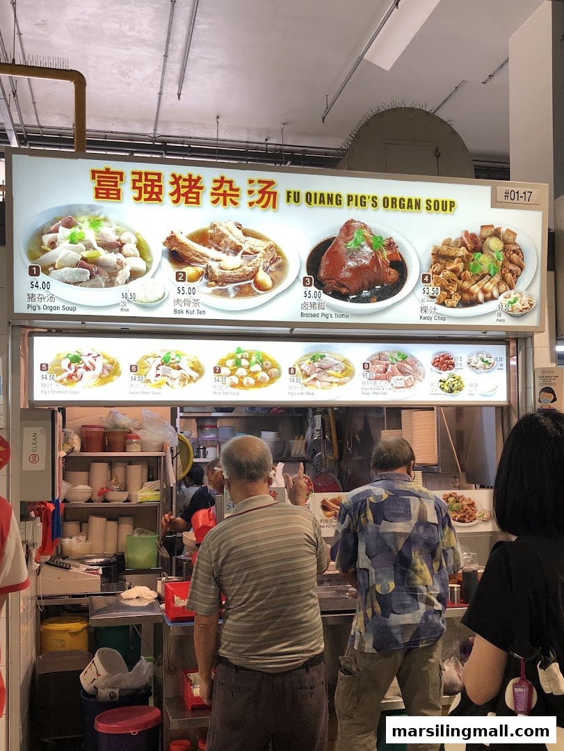 A bustling hawker stall, 'Fu Qiang Pig's Organ Soup', with customers ordering from its menu board.