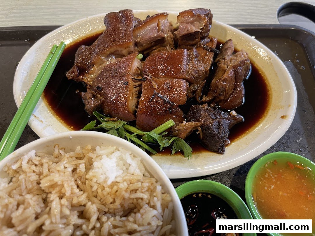 A plate of braised pork with rice, chopsticks, and dipping sauces.
