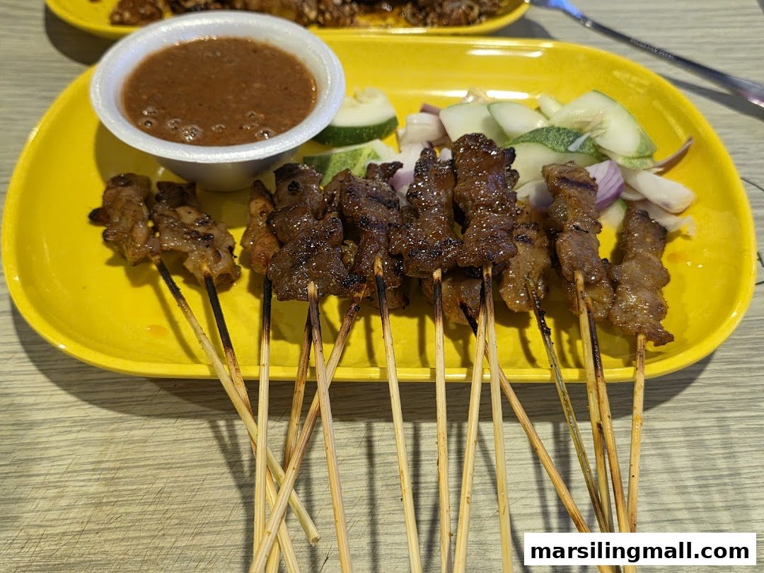 A vibrant yellow plate holds grilled satay skewers with peanut sauce, cucumber, and onions.