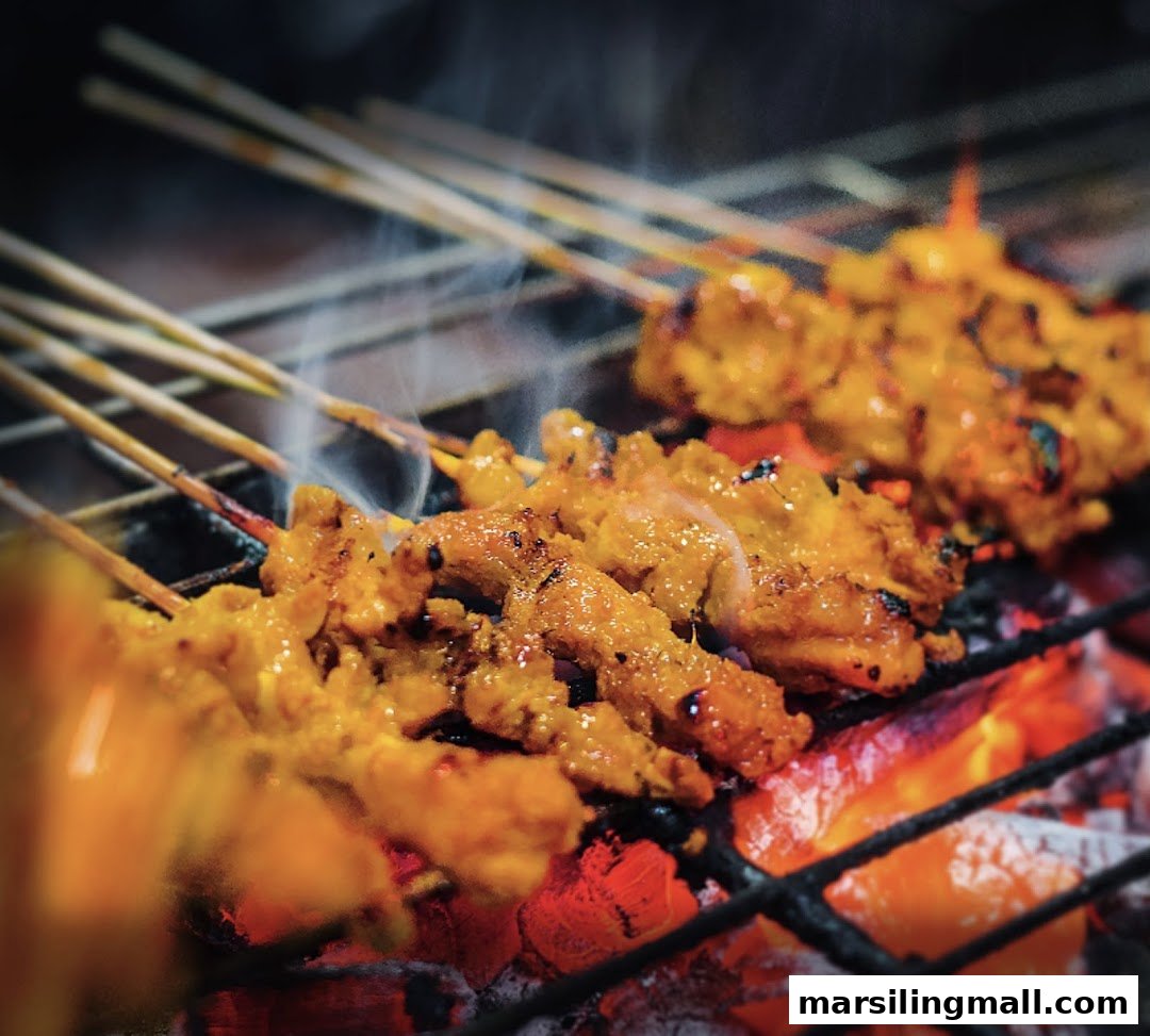 Close-up of delicious satay skewers grilling over hot charcoal with smoke rising.