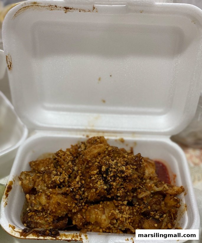 A close-up of a takeaway box filled with rojak, generously topped with crushed peanuts.