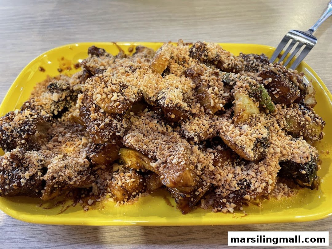 A vibrant yellow plate filled with saucy Rojak, generously topped with crushed peanuts.