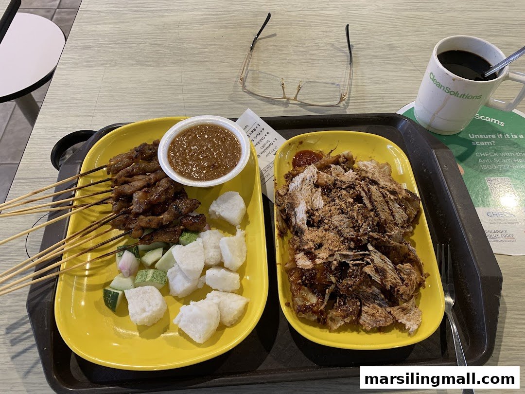 A delicious meal featuring satay skewers, rojak, and a drink on a table.