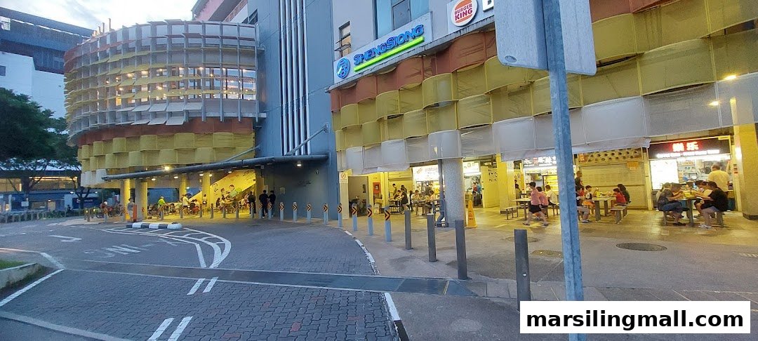Exterior view of a bustling commercial building featuring a supermarket and various food stalls.